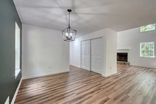 a view of an empty room with a window and wooden floor