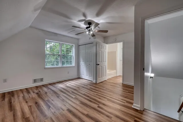 an empty room with wooden floor fan and windows