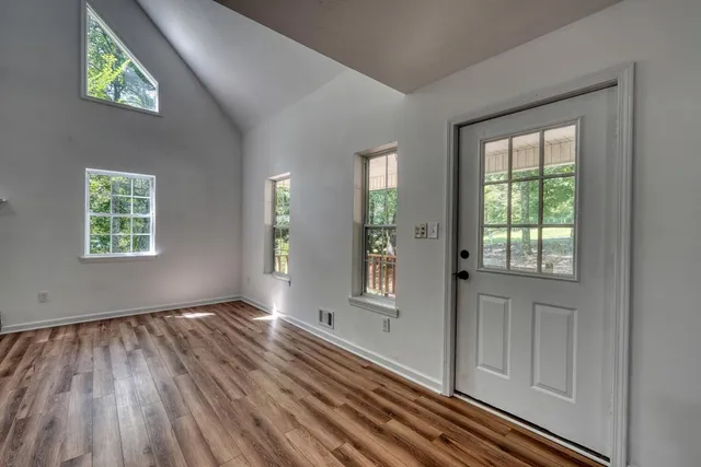an empty room with wooden floor fireplace and windows