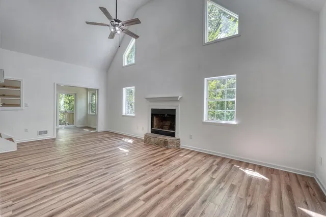 a view of empty room with wooden floor and fan