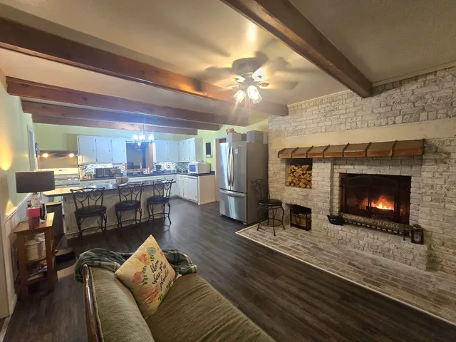 a living room with stainless steel appliances furniture a fireplace and a flat screen tv