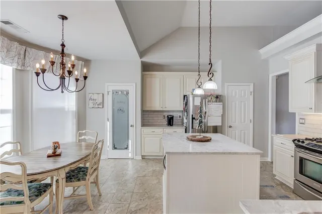 a kitchen with stainless steel appliances a table and chairs in it