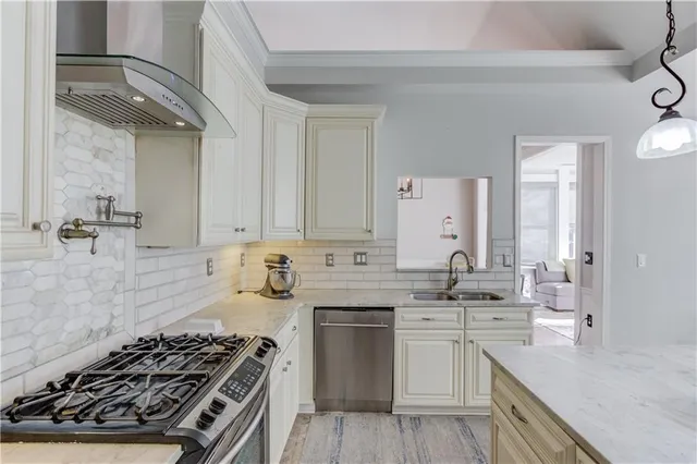 a kitchen with stainless steel appliances a sink dishwasher stove and white cabinets