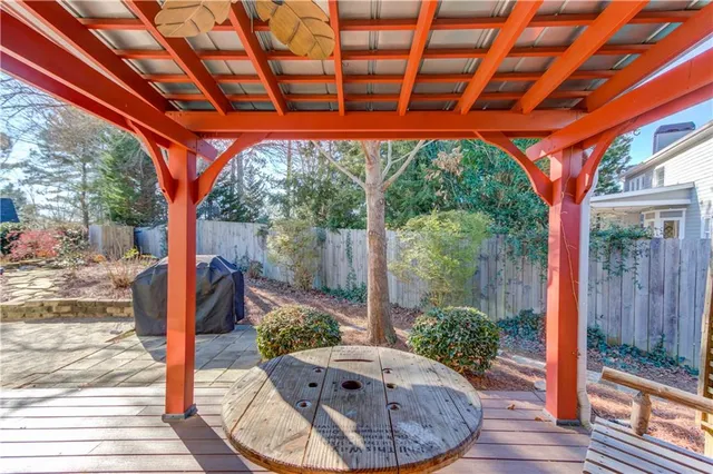 a view of a patio with table and chairs potted plants with wooden floor and fence