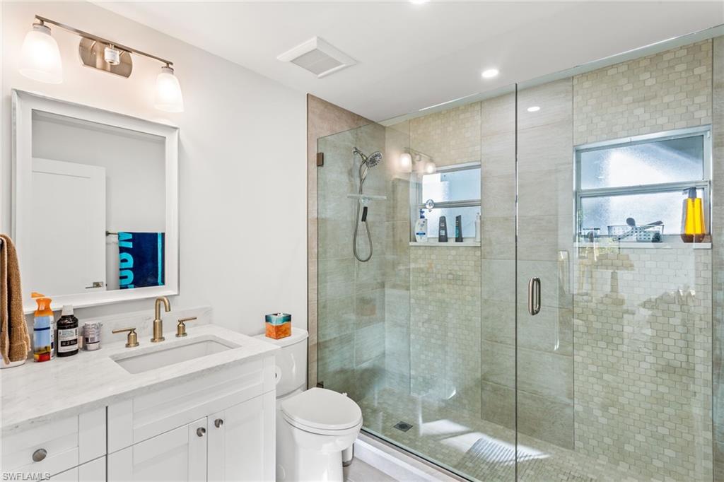 27682 Imperial River Road, Unit CH1 Bonita Springs, FL 34134 - Photo 8 of 24 a bathroom with a shower sink vanity mirror and toilet