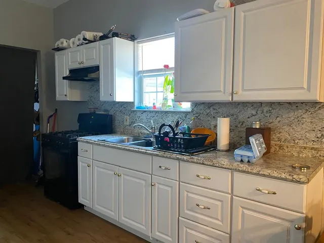a kitchen with granite countertop white cabinets and a sink