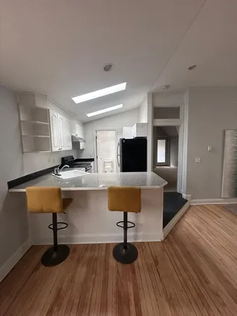 a living room with kitchen island granite countertop wooden floor and stainless steel appliances