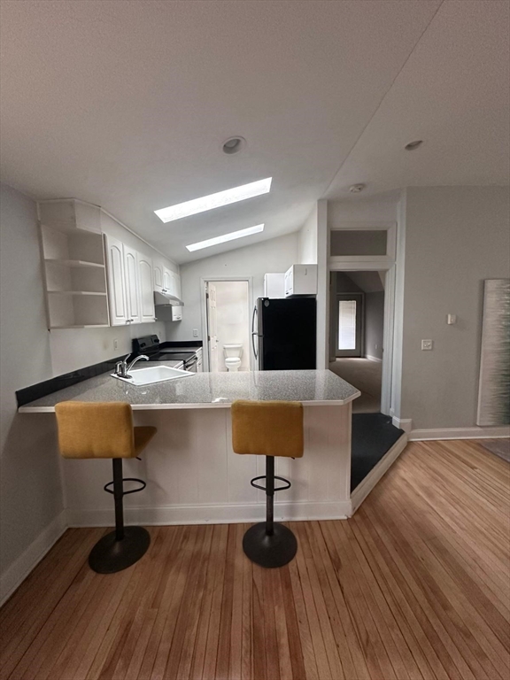 1295 Millbury Street, Unit B Worcester, MA 01607 - Photo 8 of 28 a living room with kitchen island granite countertop wooden floor and stainless steel appliances