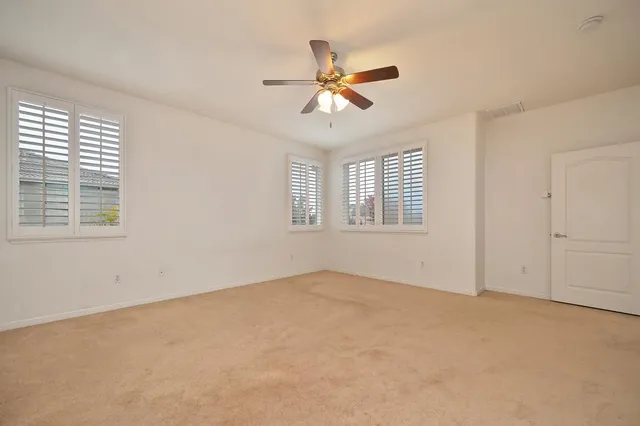 an empty room with windows and fan
