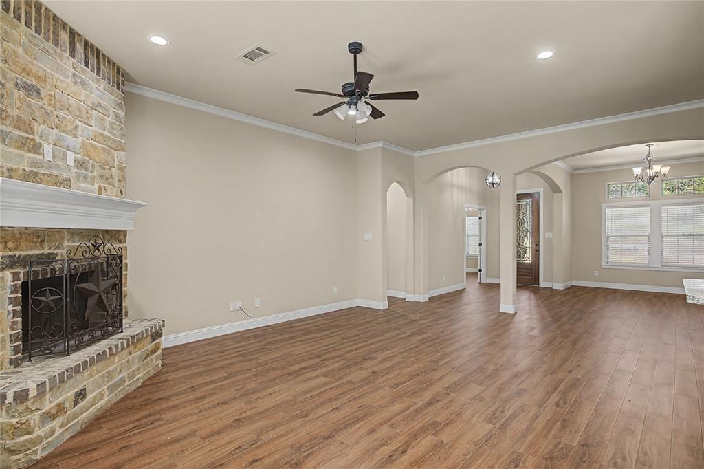 143 Wrigley Drive Springtown, TX 76082 - Photo 12 of 38 Living room featuring wood burning stone fireplace, raised hearth, wood like flooring, and ceiling fan, open to formal dining area or study.