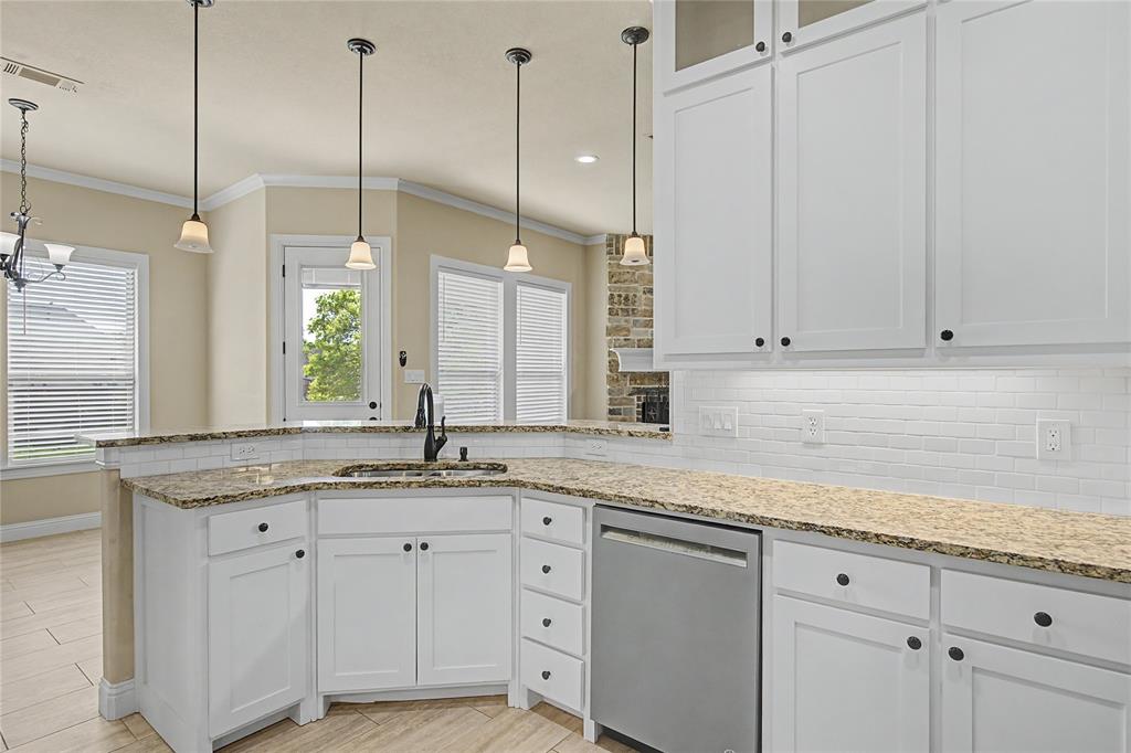 143 Wrigley Drive Springtown, TX 76082 - Photo 16 of 38 Kitchen featuring white cabinetry, pendant lighting, stainless steel appliances, crown molding, light granite countertops, and backsplash.