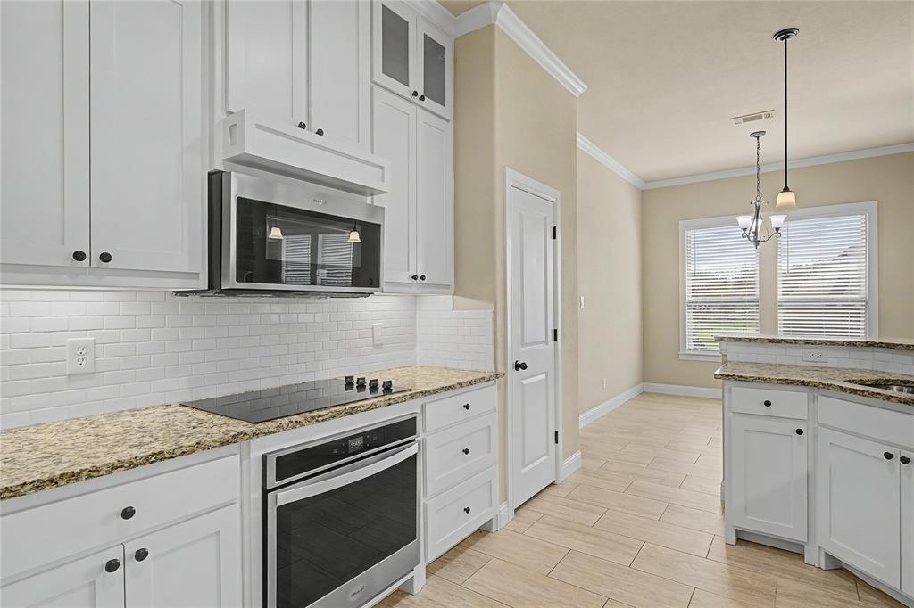 143 Wrigley Drive Springtown, TX 76082 - Photo 17 of 38 Kitchen with a peninsula, decorative backsplash, white cabinets, and ornamental molding