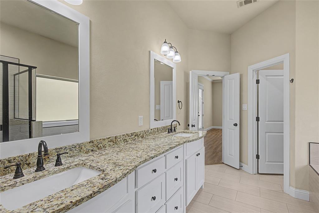 143 Wrigley Drive Springtown, TX 76082 - Photo 26 of 38 a bathroom with a granite countertop double vanity sink a mirror and a shower