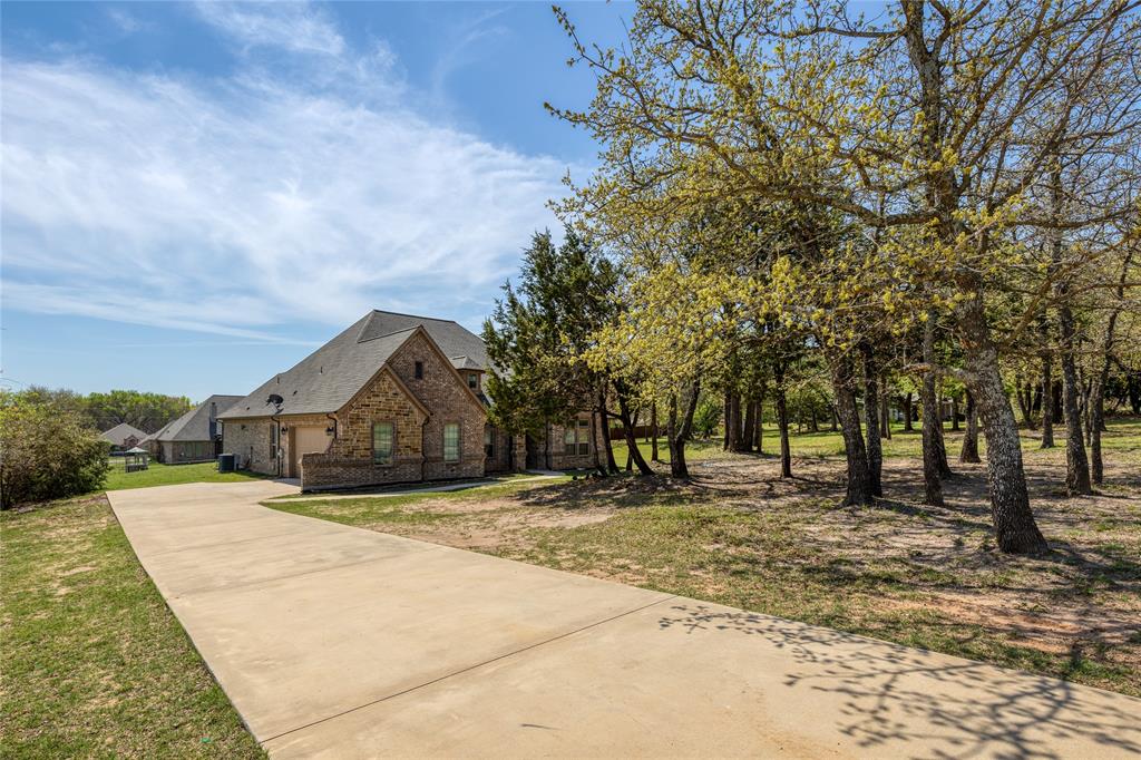 143 Wrigley Drive Springtown, TX 76082 - Photo 36 of 38 View of home's exterior featuring brick & stone siding, large driveway, and a yard