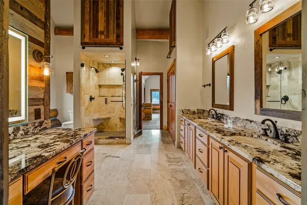 a spacious bathroom with a granite countertop double vanity sink a mirror and a shower