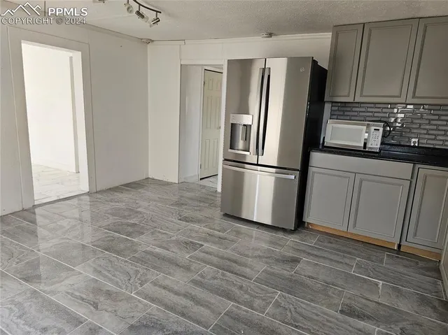 a kitchen with granite countertop a refrigerator and a sink