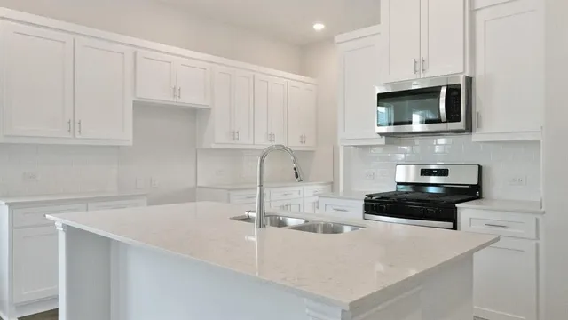 a kitchen with stainless steel appliances a stove a microwave a sink and cabinets