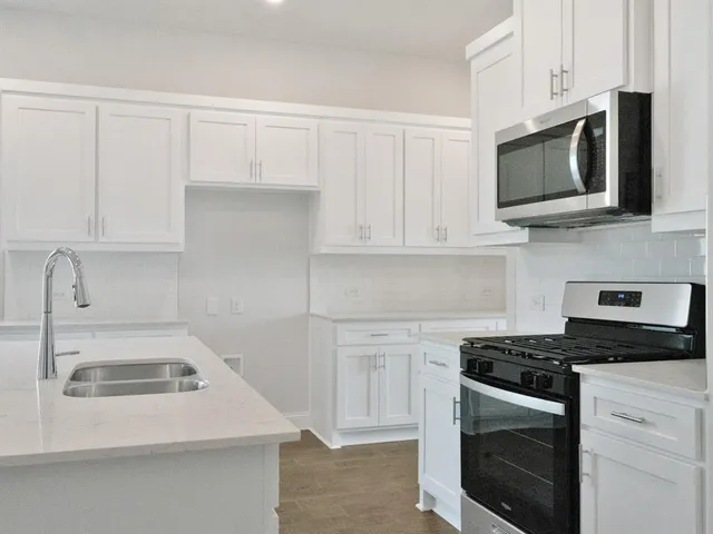 a kitchen with white cabinets and stainless steel appliances