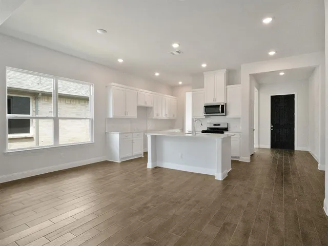 a view of kitchen with kitchen island stainless steel appliances wooden cabinets and window