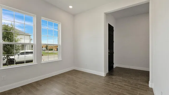 an empty room with wooden floor and windows