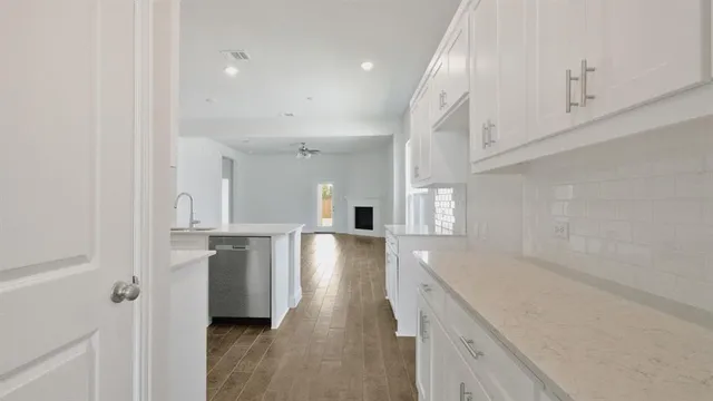 a view of a kitchen with a sink and dishwasher a refrigerator with white cabinets