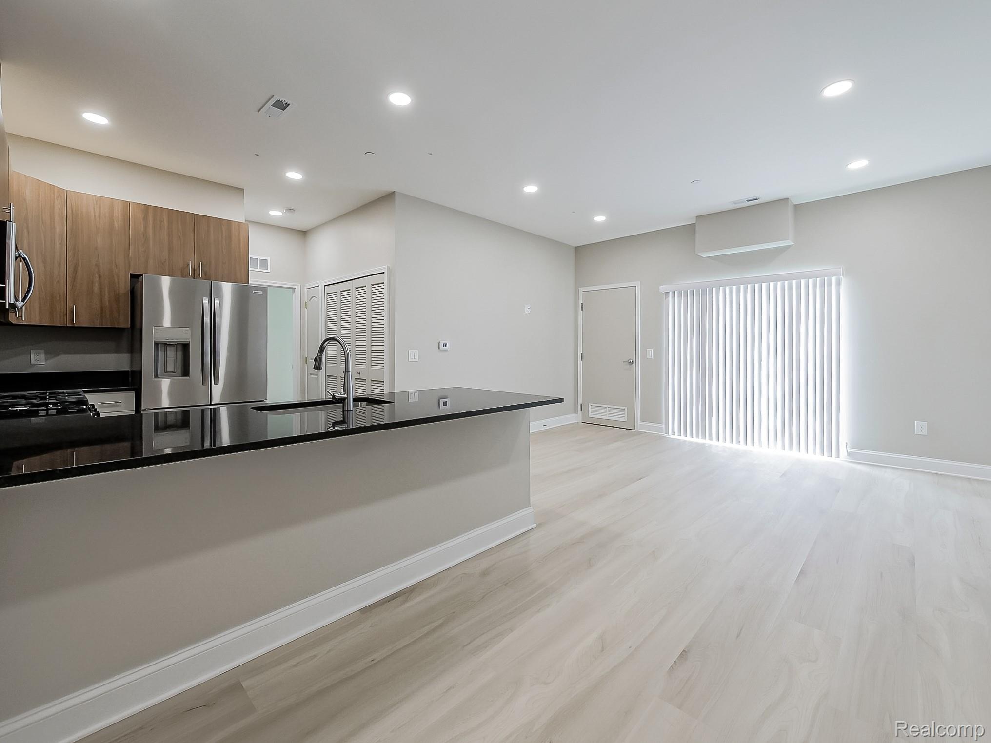 31480 Warren Road, Unit 101 Westland, MI 48185 - Photo 26 of 26 Kitchen with stainless steel appliances, light wood-type flooring, open floor plan, dark stone counters, and modern cabinets