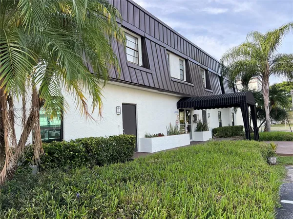 a view of a house with a yard and potted plants