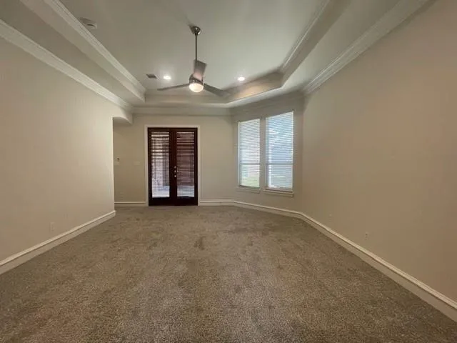 an empty room with windows and chandelier fan