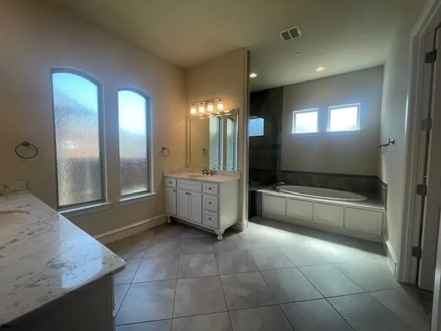 a bathroom with a tub a sink and mirror