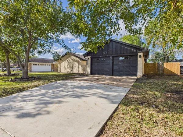 front view of a house with a dirt yard and a large tree