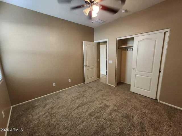 an empty room with closet and a ceiling fan