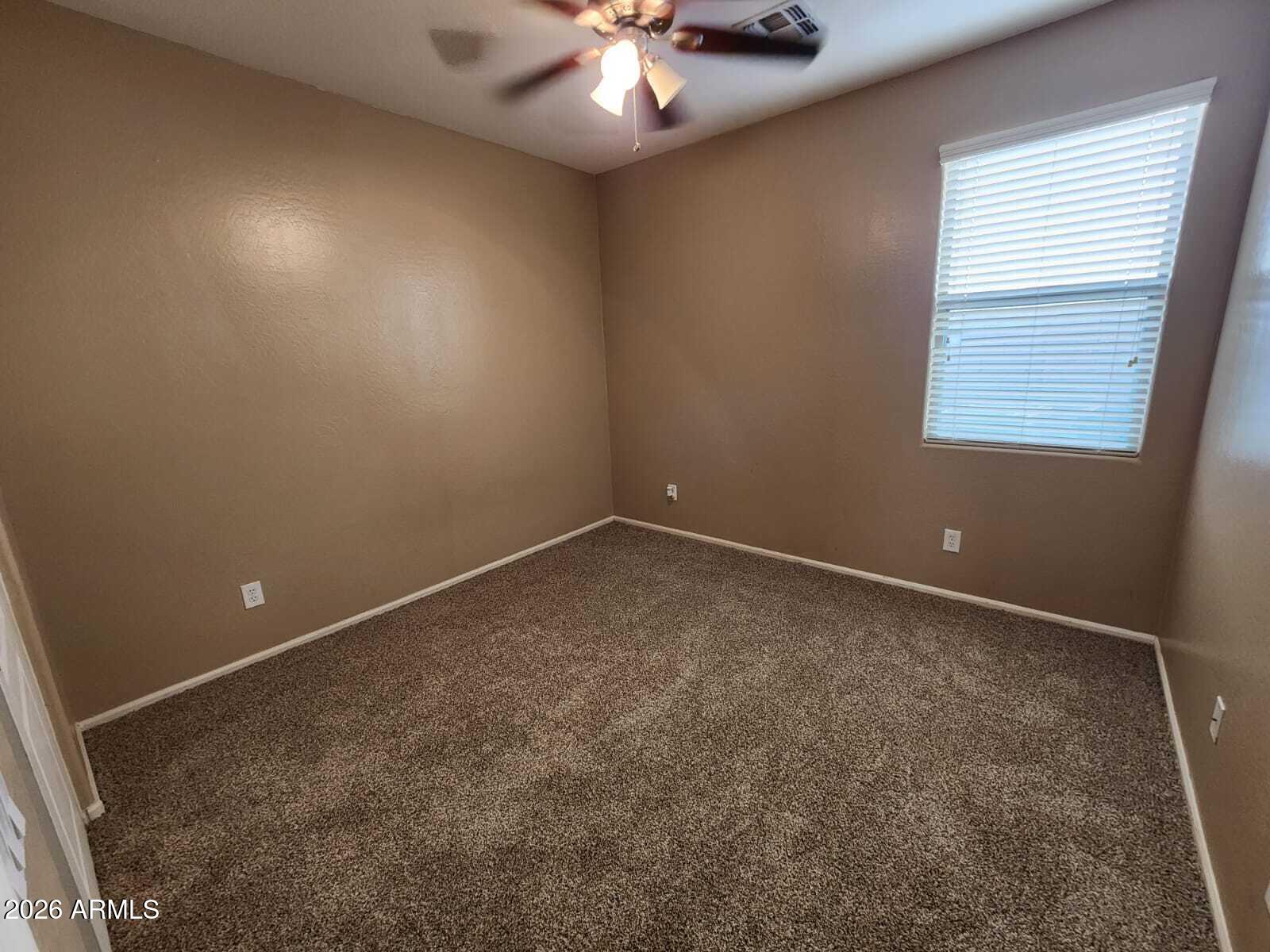 7643 West Charter Oak Road Peoria, AZ 85381 - Photo 18 of 27 an empty room with a chandelier fan and windows