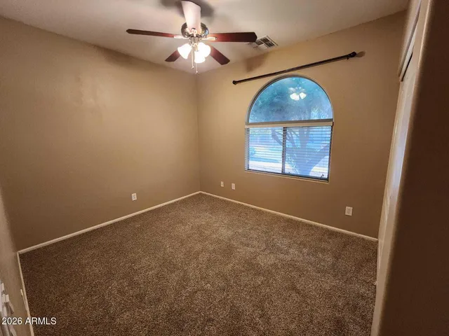 an empty room with a chandelier fan and windows