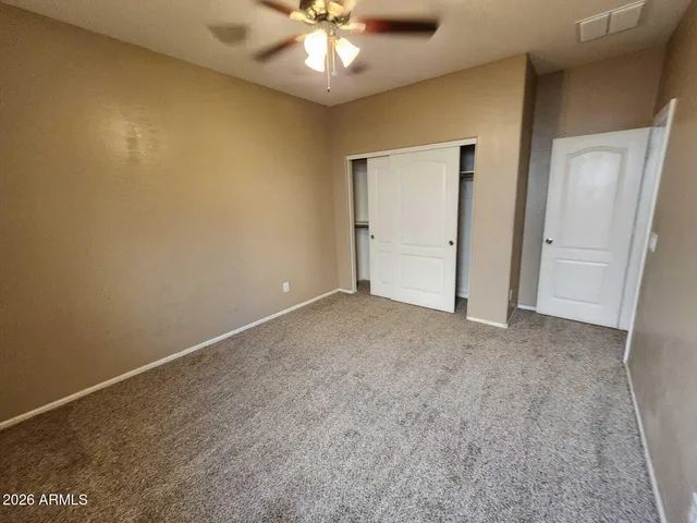 an empty room with a chandelier fan and a bathroom