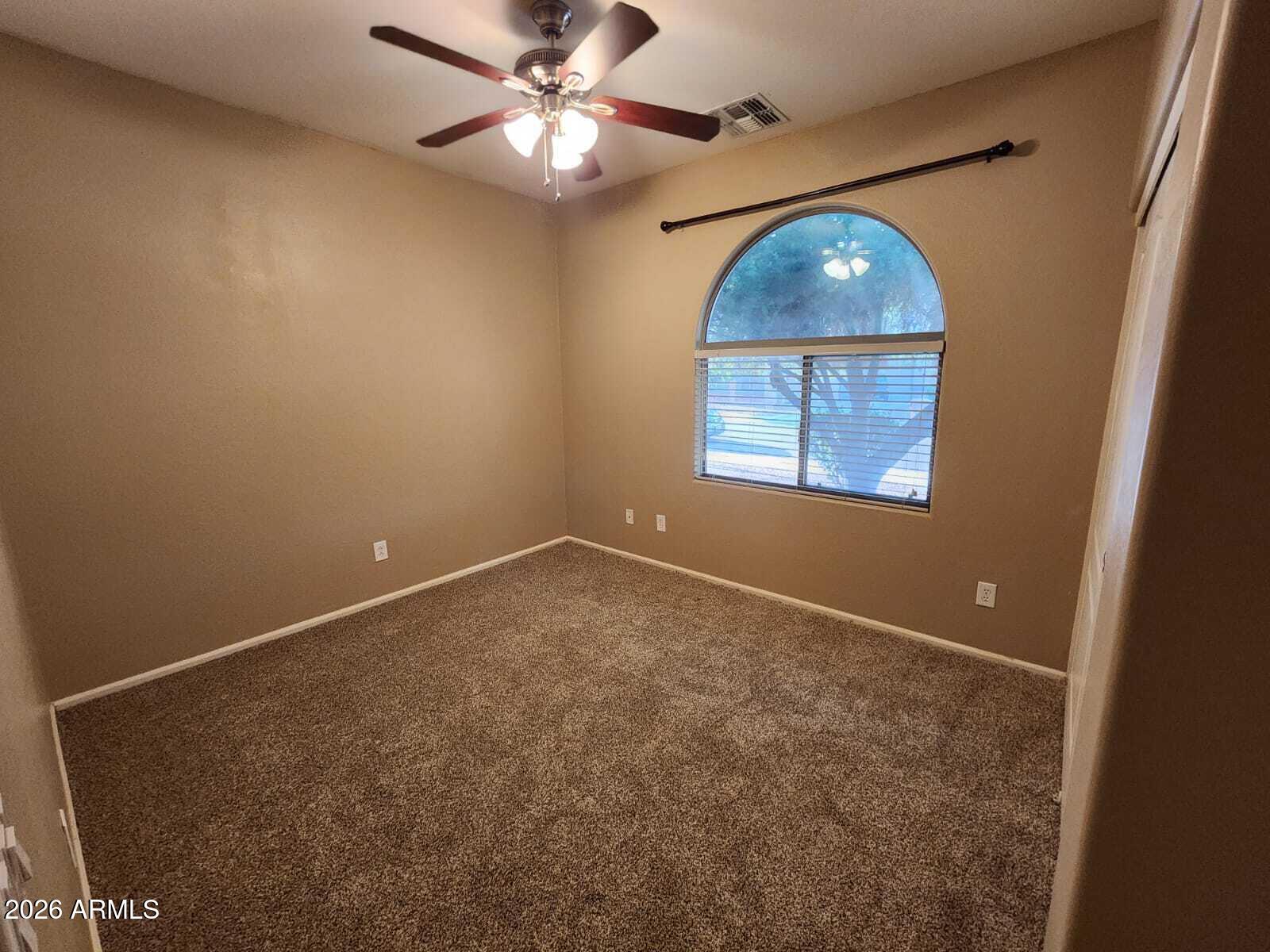 7643 West Charter Oak Road Peoria, AZ 85381 - Photo 10 of 27 an empty room with a chandelier fan and a large window