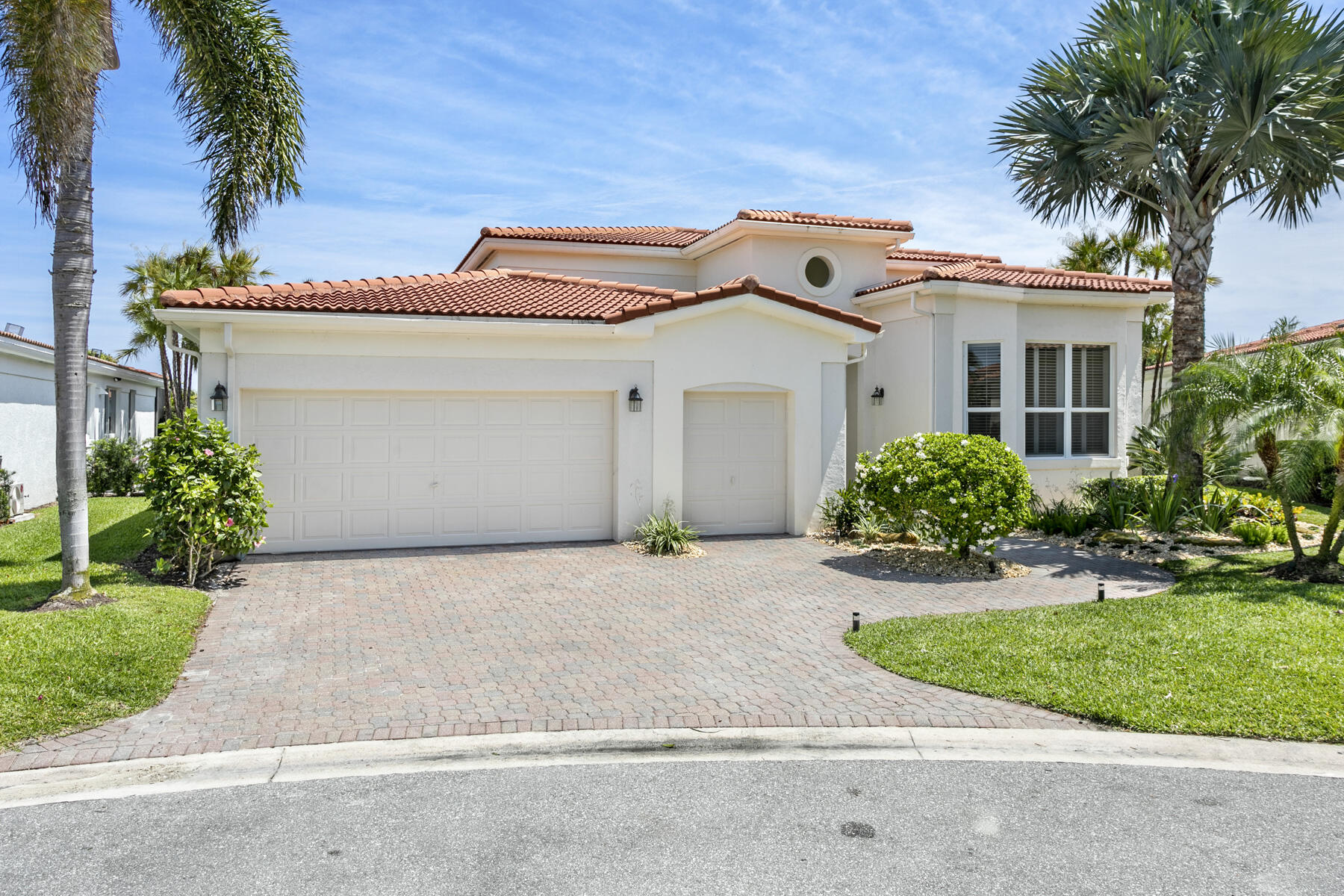 15810 Windrift Drive Jupiter, FL 33477 - Photo 2 of 52 a view of a white house with a large tree and plants