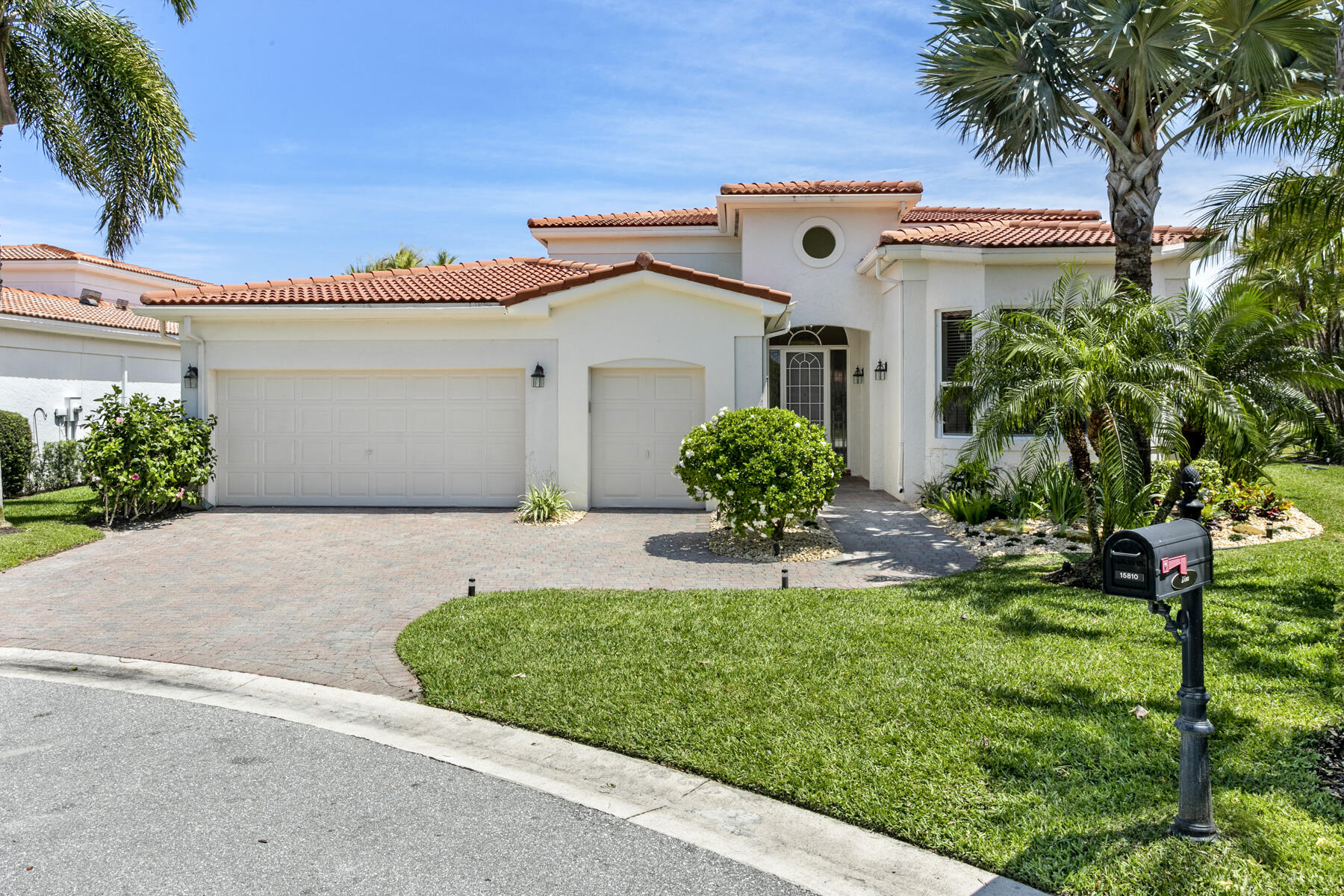 15810 Windrift Drive Jupiter, FL 33477 - Photo 3 of 52 a front view of a house with a yard and potted plants