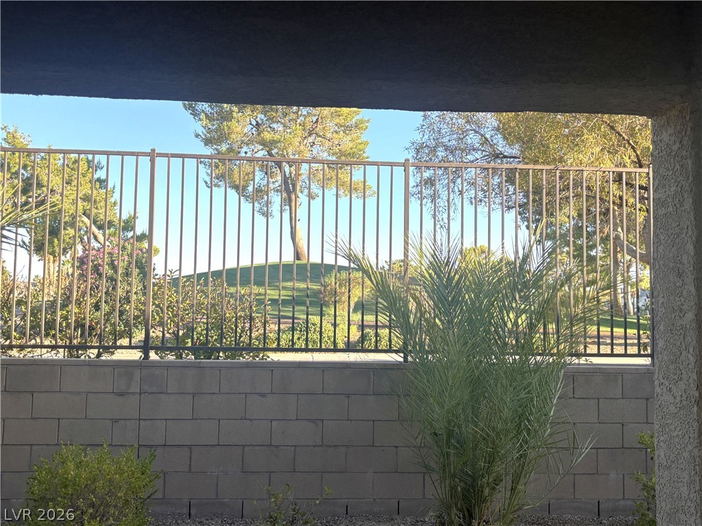 121 Elm Reed Avenue Las Vegas, NV 89113 - Photo 29 of 30 A private, secure yard with a sturdy fence overlooking a serene, verdant landscape.