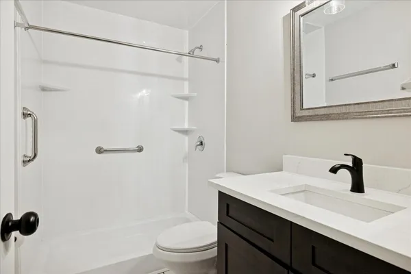 a bathroom with a sink a toilet a mirror and shower