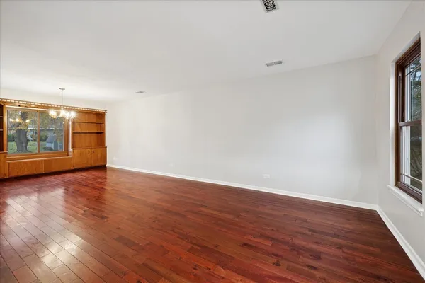 a view of an empty room with window and wooden floor