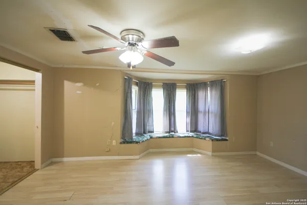 a view of an empty room with window and wooden floor