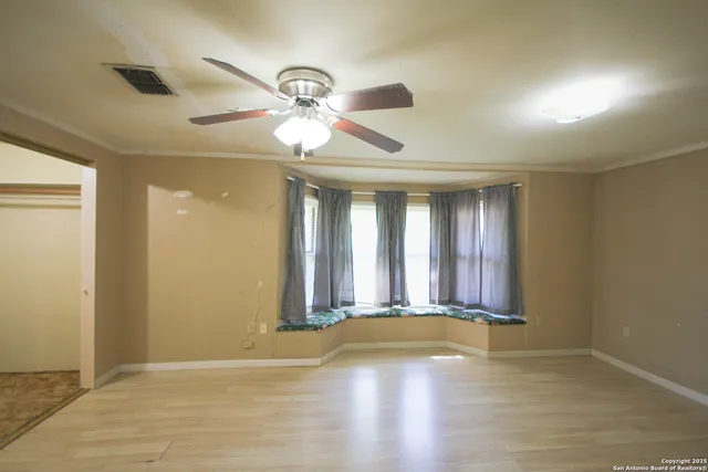 a view of an empty room with window and wooden floor