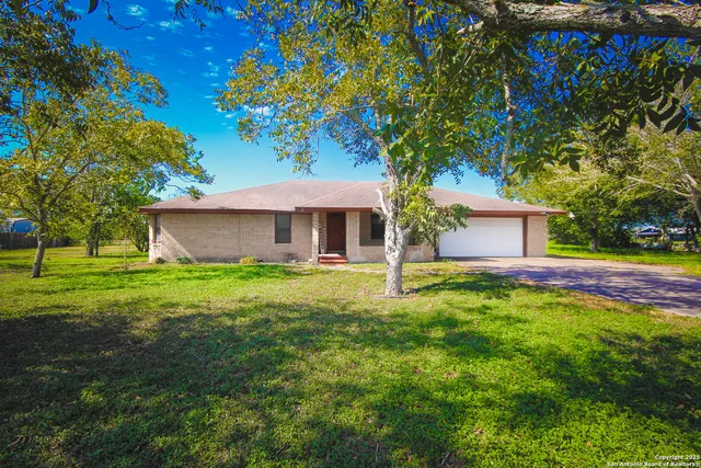 a front view of a house with yard and tree