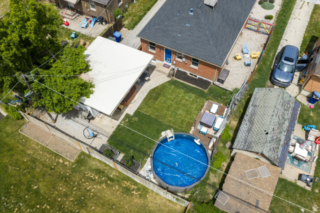 961 33rd Street Ogden, UT 84403 - Photo 4 of 39 Brick exterior featuring a dark shingle roof, a dedicated pool deck, and a circular above-ground pool