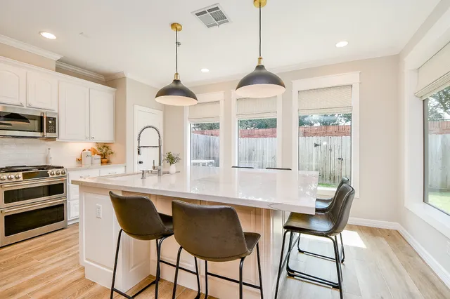 a kitchen with stainless steel appliances a stove a sink a window and chairs
