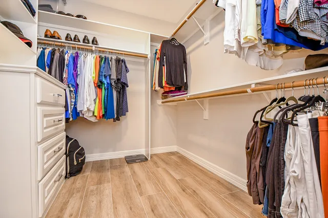 a view of walk in closet with clothes and shoes