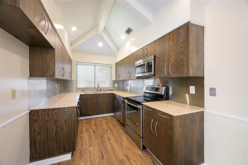 6512 Mc Cormick Ranch Court Plano, TX 75023 - Photo 14 of 29 a kitchen with stainless steel appliances a sink dishwasher a stove top oven a refrigerator with grey cabinets and wooden floor