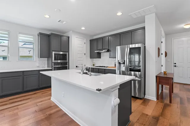 a large kitchen with stainless steel appliances a refrigerator and a stove top oven