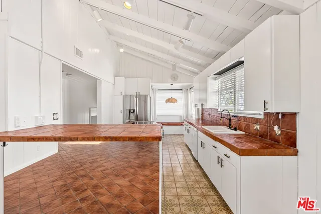 a large white kitchen with kitchen island granite countertop a large counter top and sink