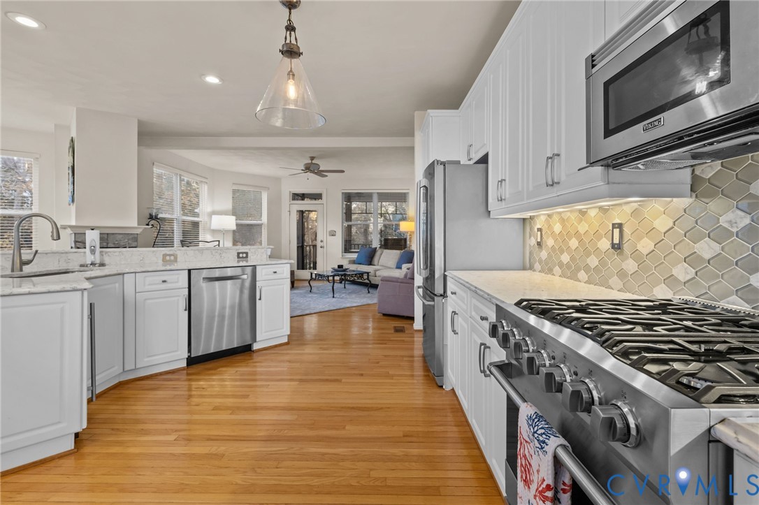 3973 West Stratford Road Virginia Beach, VA 23455 - Photo 14 of 45 a kitchen with stainless steel appliances a sink dishwasher stove and white cabinets with wooden floor